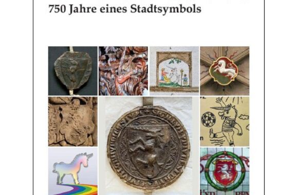 Ein Einhorn-Symbol vor historischen Gebäuden mit Jubiläumsbanner und Buchpräsentation.