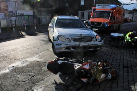 Motorradunfall: Schwer verletzter Fahrer, Rettungshubschrauber, beschädigte Fahrzeuge, Polizei ermittelt.