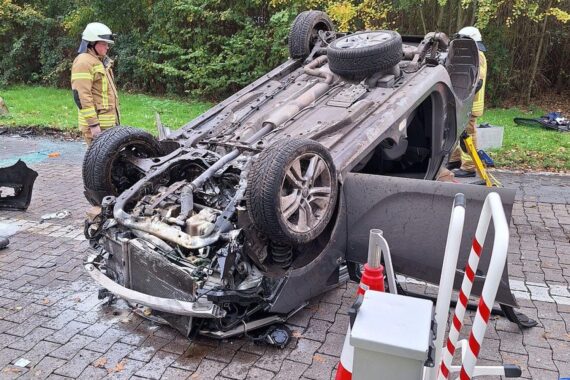Ein umgekipptes Auto auf Rastplatz, Feuerwehr im Einsatz, Verletzte werden behandelt.