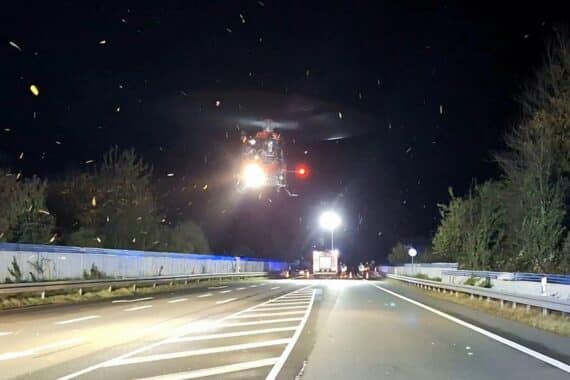 Rettungshubschrauber über Unfallstelle mit Feuerwehr und Rettungsdienst, Verletzte werden versorgt.