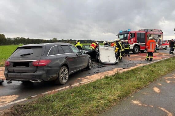 Unfallstelle mit zwei Fahrzeugen, Feuerwehr im Einsatz, Verletzte werden gerettet.