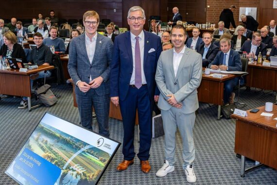 Drei Männer stehen zusammen, verabschieden und begrüßen sich im Kreistag mit ernsten Mienen.