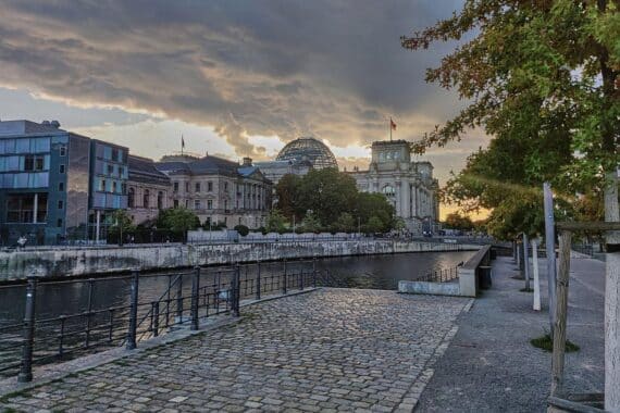 Sonnenuntergang über dem Reichstagsgebäude, umhüllt von dichten Wolken und frischem Wind.