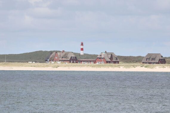 Wolkiger Himmel mit milden Temperaturen, Leuchtturm an der Küste, Sprühregen möglich.