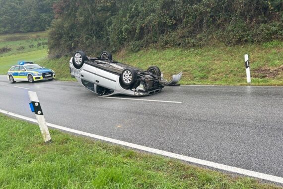 Überschlagener PKW auf der Straße, Einsatzkräfte sichern Unfallstelle, keine Verletzten.