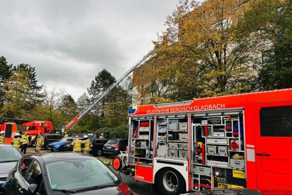 Feuerwehrleute löschen Brand in Mehrfamilienhaus; Rauch steigt aus einem Fenster. Verletzte Personen.
