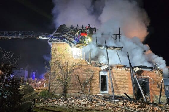 Zerstörtes Wohnhaus nach Explosion, Feuerwehr im Einsatz, starke Rauchentwicklung und Trümmer.