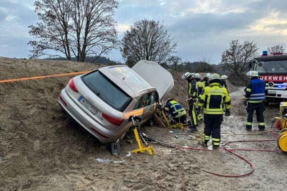 Feuerwehr befreit Fahrerin nach Unfall, Fahrzeug liegt auf der Seite, Einsatzkräfte arbeiten.