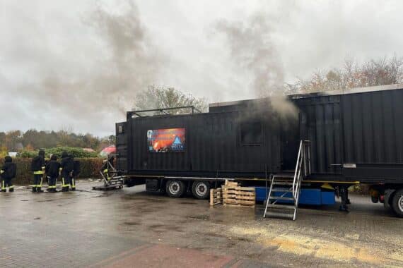 Feuerwehrleute trainieren in beheiztem Container das Öffnen brennender Zimmertüren und Brandbekämpfung.