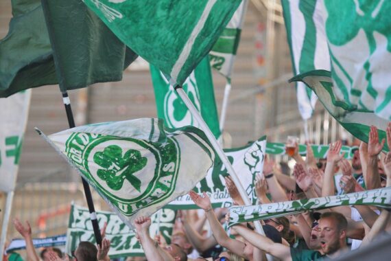 Fans der Greuther Fürth jubeln, während die Vereinsführung finanzielle Herausforderungen und Veränderungen bespricht.