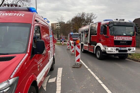 Rettungskräfte befreien Mann aus Baugrube, Feuerwehr im Einsatz, Drehleitern und Holzverbau sichtbar.