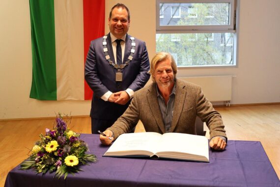 Oberbürgermeister und Henning Baum übertragen Eintrag ins Goldene Buch während Kurzfilmfestival in Hagen.