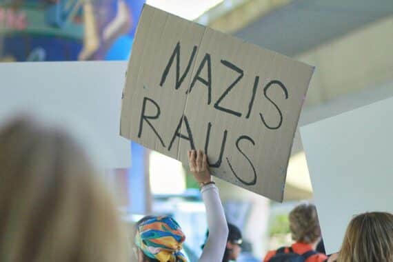 Protestierende Menschen, Polizeieinsatz, Konfrontation, antifaschistische Aktion, symbolische Darstellung von Widerstand.