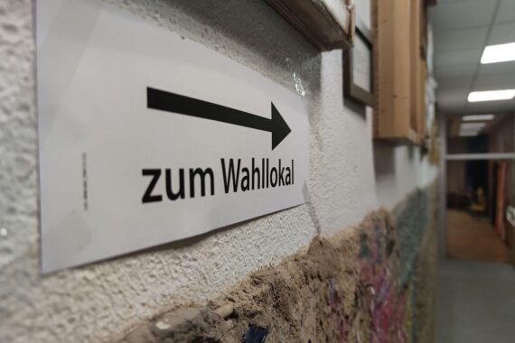 Wahllokal mit Wählern, Symbol für politische Partizipation und Absenkung des Wahlalters auf 16.