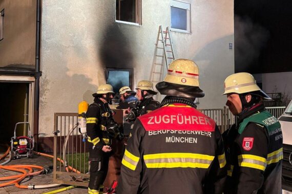 Einsatzkräfte der Feuerwehr löschen Brand und retten verletzten Mann aus Mehrfamilienhaus in München.