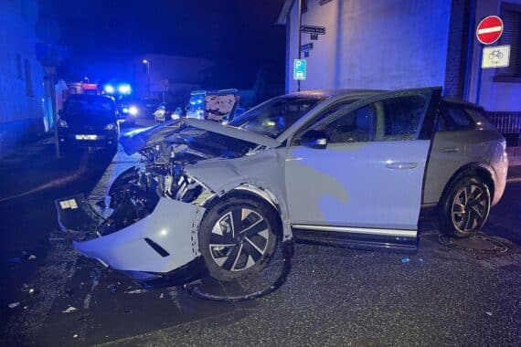 Zwei stark beschädigte Autos, Unfallstelle, umstehenden Schaden und Polizeiabsperrungen am Straßenrand.