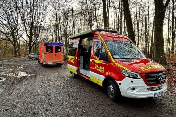 Rettungseinsatz im Wald: Feuerwehr und Notarzt helfen verletztem Wanderer während Sportveranstaltung.