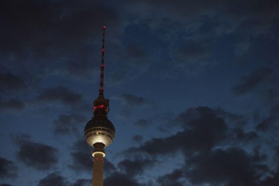 Berliner Fernsehturm bei Nacht, umgeben von dichten Wolken und städtischer Atmosphäre.