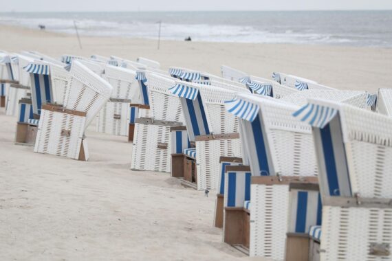 Strandkörbe am Strand unter wechselhaftem Herbstwetter mit frostigen Temperaturen und dunklen Wolken.