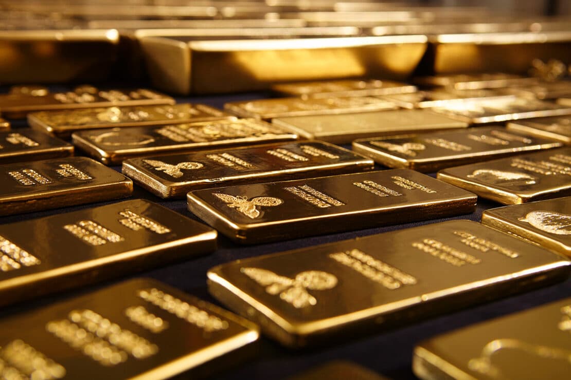 Flache Goldbarren nebeneinander auf dunkler Unterlage
