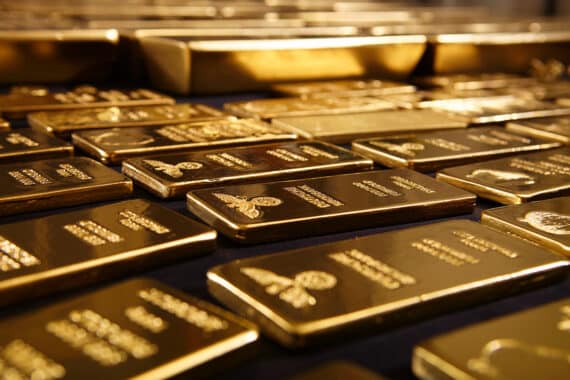 Flache Goldbarren nebeneinander auf dunkler Unterlage
