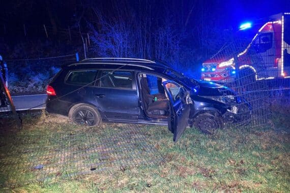 Ein beschädigtes Auto prallt gegen einen Zaun, Unfallstelle mit Absperrung und Polizei.