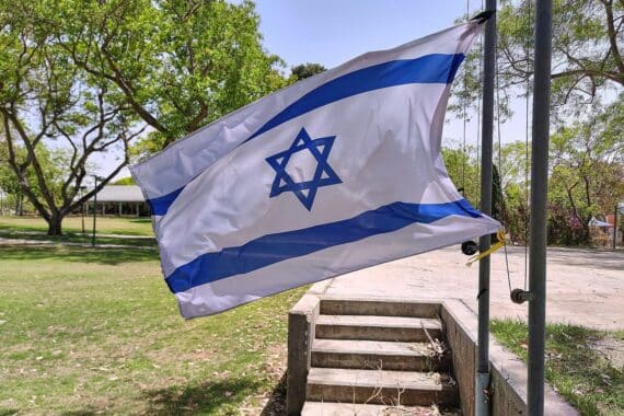 Israelische Fahne in Kibbuz, symbolisiert Siedlungsbau im Westjordanland und internationale Spannungen.