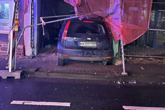 Auto prallt in Schaufenster, Baugerüst droht einzustürzen, Verletzte: Fahrerin, keine weiteren Personen.