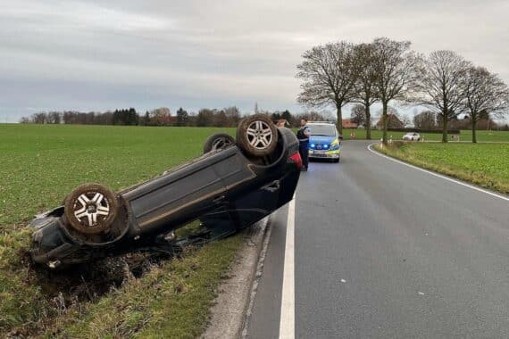 Älterer VW Golf auf dem Dach liegend, Unfallstelle mit Polizei und Abschleppfahrzeug.