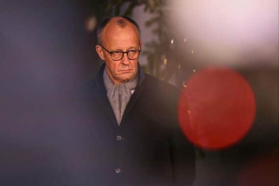 Friedrich Merz steht entspannt vor einem festlich geschmückten Weihnachtsbaum.