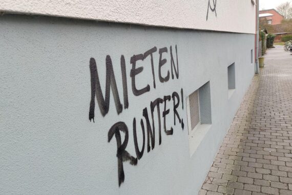 Graffiti mit dem Schriftzug "Mieten runter", symbolisiert Protest gegen steigende Wohnkosten in Deutschland.