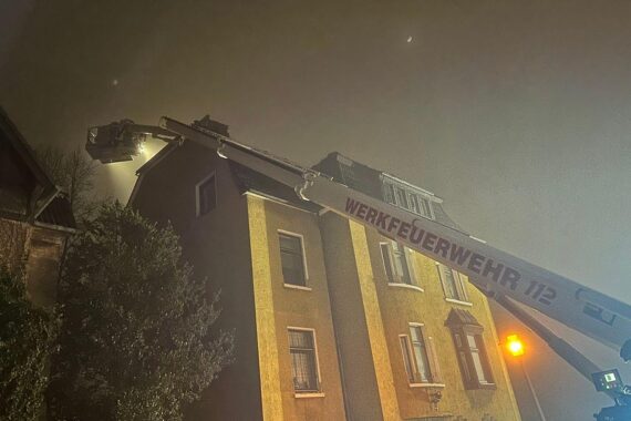 Dachstuhlbrand mit Feuerwehr im Einsatz, Drehleitern und Teleskopmastbühne über brennendem Gebäude.
