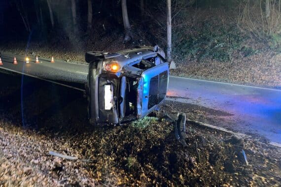 Ein überschlagenes Auto an einer Bundesstraße, Rettungsdienste sind im Einsatz.