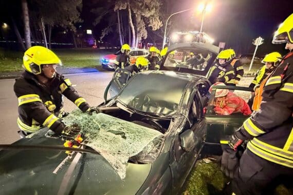 Unfallstelle mit Feuerwehr, beschädigtem Auto, Laternenmast und leicht verletzter Fahrerin in Hattersheim.