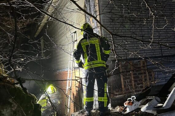 Feuerwehr öffnet Fassade eines Gebäudes, um Brand löschen und Schäden verhindern.