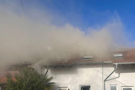 Ein brennendes Haus mit Feuerwehr und Rauch, Anwohner sollen Fenster geschlossen halten.