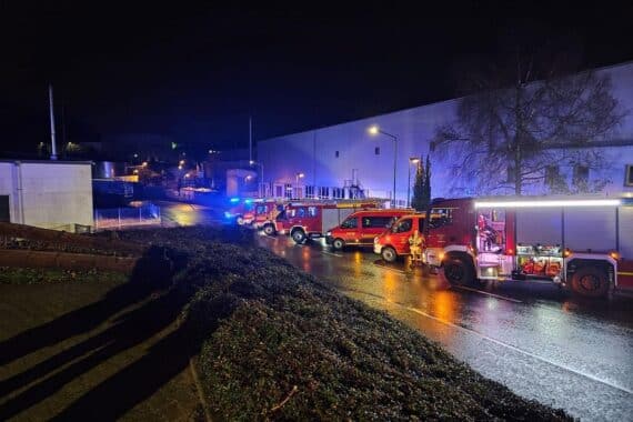 Bereitstellungsraum der Feuerwehr mit Einsatzfahrzeugen und Feuerwehrleuten in Alarmbereitschaft.