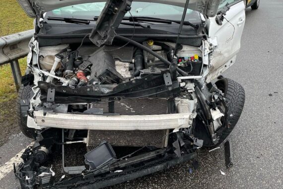 Zwei beschädigte Autos nach Unfall auf nasser Straße, Feuerwehr und Polizei vor Ort.