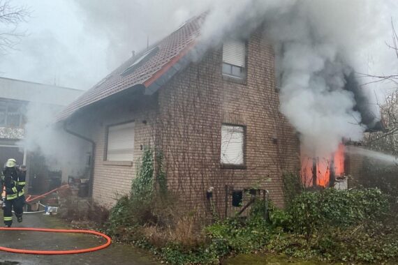 Einfamilienhaus in Dortmund-Höchsten nach einem Brand, Feuerwehr im Einsatz, stark beschädigt.