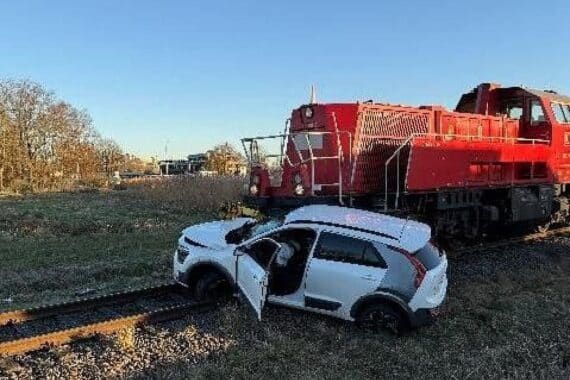 Güterzug kollidiert mit PKW am Bahnübergang, Rettungsdienste im Einsatz, ernsthafte Verletzungen.