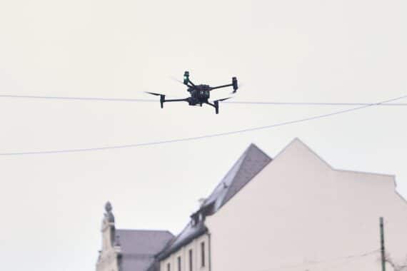 Drohne fliegt über Menschenmenge, symbolisiert Sicherheitsmaßnahmen und Schutz vor Extremismus.