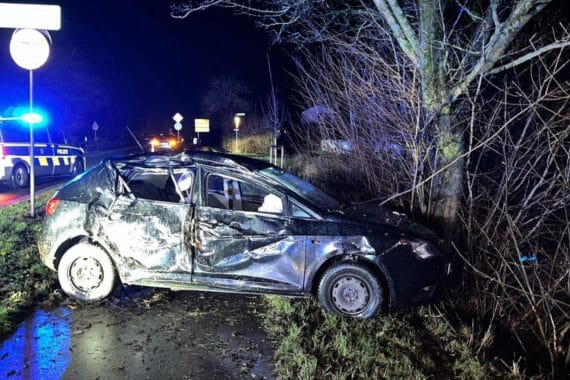 Ein beschädigter Seat, umgeben von Bäumen, Polizei vor Ort, Unfallstelle auf Bundesstraße.