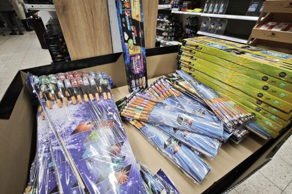 Feuerwerksstand mit festlichen Produkten, Menschen in wartender Schlange, Silvestervorfreude spürbar.