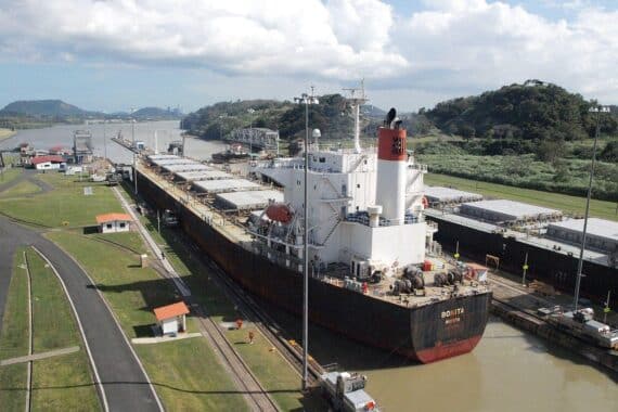 Frachtschiff im Panama-Kanal symbolisiert globalen Handel und wirtschaftliche Herausforderungen der OECD-Prognosen.