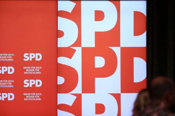 SPD-Logo mit Protestsymbolen und Menschen, die für Mitgliederrechte und Bürgergeldreform demonstrieren.