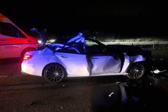 Ein schwer beschädigter Mercedes nach einem Autobahnunfall, Polizei-Absicherung und Rettungseinsatz sichtbar.