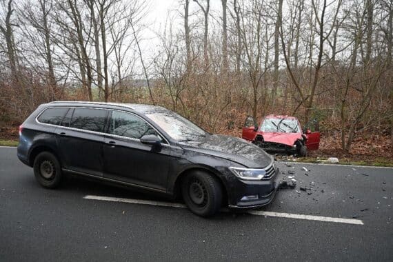 Zwei beschädigte Autos nach frontalem Unfall, Rettungswagen und Polizei am Einsatzort.