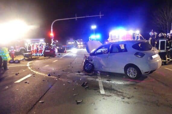 Zwei kollidierte Autos an Kreuzung, Polizei vor Ort, Verletzte werden behandelt.