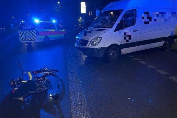 Unfallstelle mit Polizei, Rettungswagen und beschädigtem Rad, Radfahrerin verletzt, Transporter beteiligt.