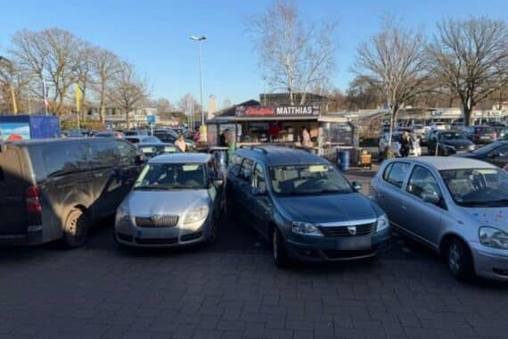 Unfall auf Parkplatz: Seniorenfahrzeug erfasst Fußgänger, mehrere Autos beschädigt. Verletzte in Krankenhaus.